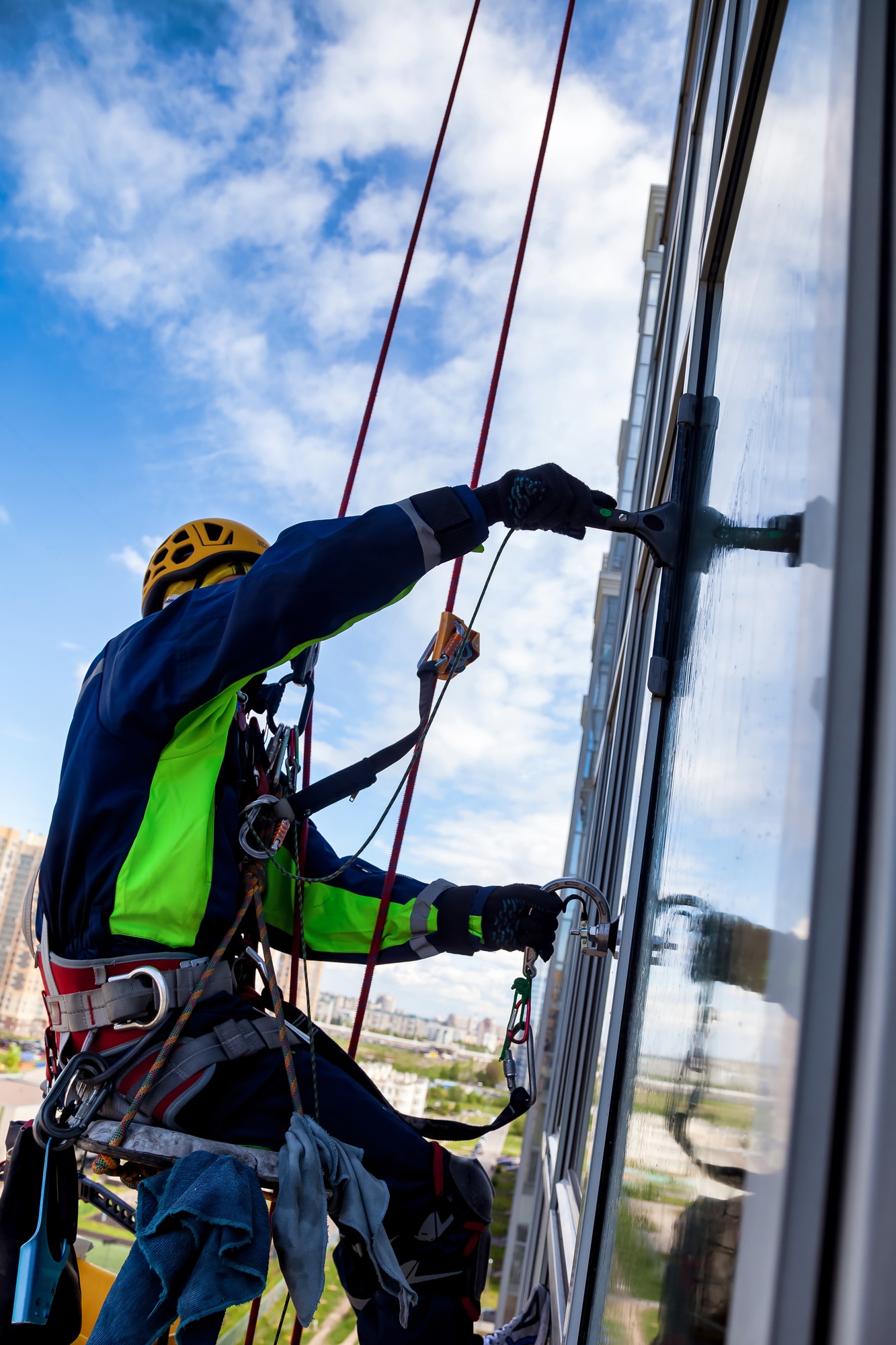 Occupational industrial mountaineering worker washing facade glazing